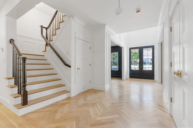 entryway featuring french doors, light parquet flooring, and crown molding