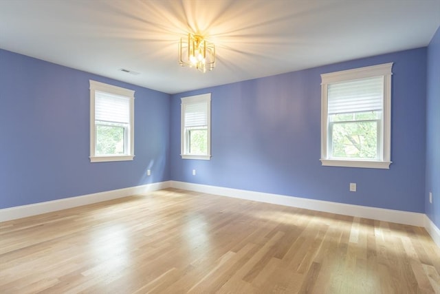 spare room featuring light hardwood / wood-style flooring and a chandelier