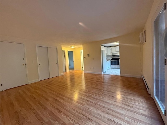 unfurnished living room with light wood-type flooring, baseboards, and a baseboard radiator