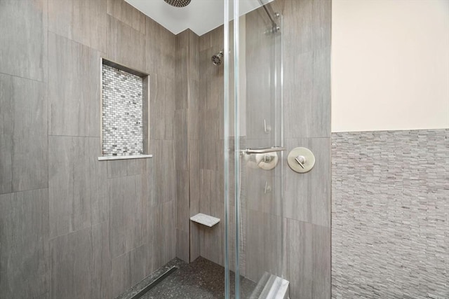 bathroom featuring a shower stall and tile walls