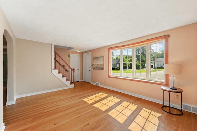 45 Donamor Ln, East Longmeadow, MA 01028 - unfurnished living room with arched walkways, baseboards, wood finished floors, and stairway