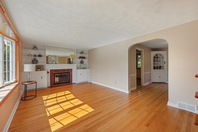 45 Donamor Ln, East Longmeadow, MA 01028 - unfurnished living room with arched walkways, plenty of natural light, light wood-style flooring, and a fireplace