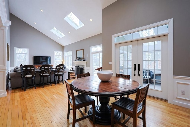 dining room featuring plenty of natural light, french doors, a fireplace, and light wood-style floors