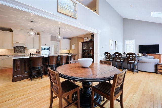 dining area featuring a high ceiling, light wood-type flooring, and recessed lighting