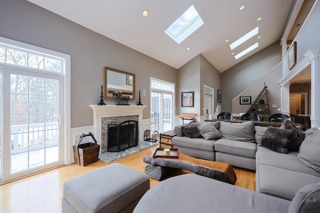 living room featuring a skylight, light wood finished floors, recessed lighting, a premium fireplace, and high vaulted ceiling