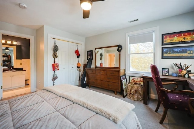 bedroom featuring ensuite bathroom, light carpet, visible vents, a ceiling fan, and a closet