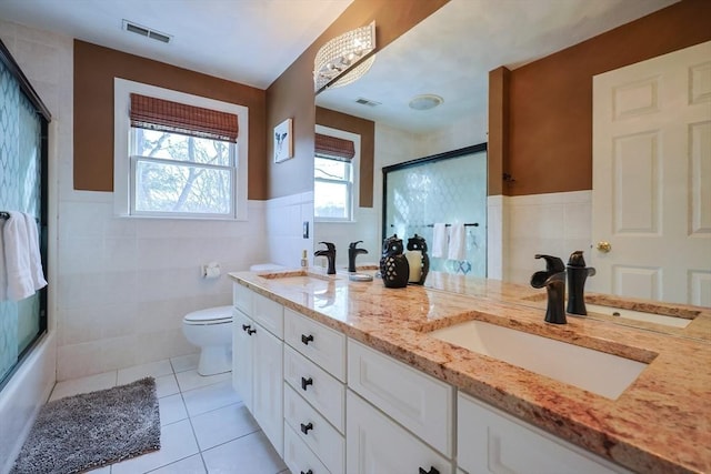 bathroom with tile patterned flooring, visible vents, a sink, and tile walls