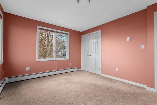 unfurnished bedroom with carpet flooring, a closet, and a baseboard heating unit