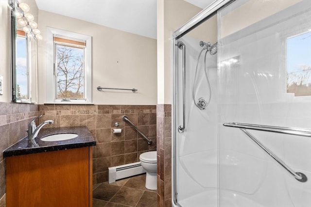 bathroom featuring vanity, tile patterned floors, baseboard heating, walk in shower, and tile walls