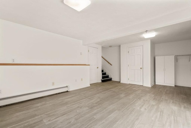 basement featuring light wood-type flooring and baseboard heating