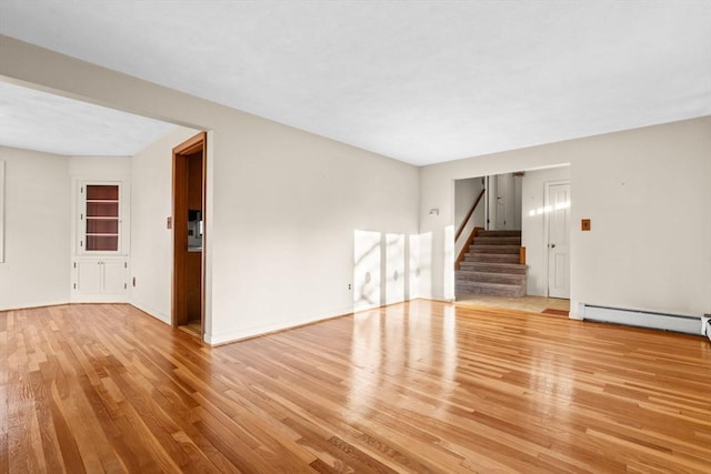 empty room with light wood-type flooring and a baseboard heating unit