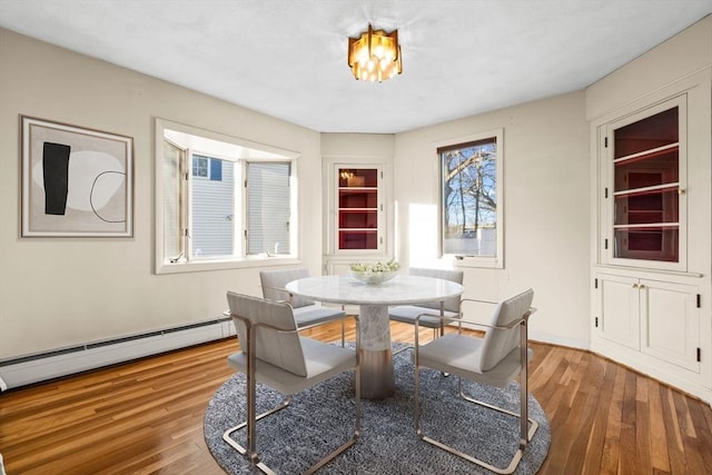 dining space featuring wood-type flooring and baseboard heating