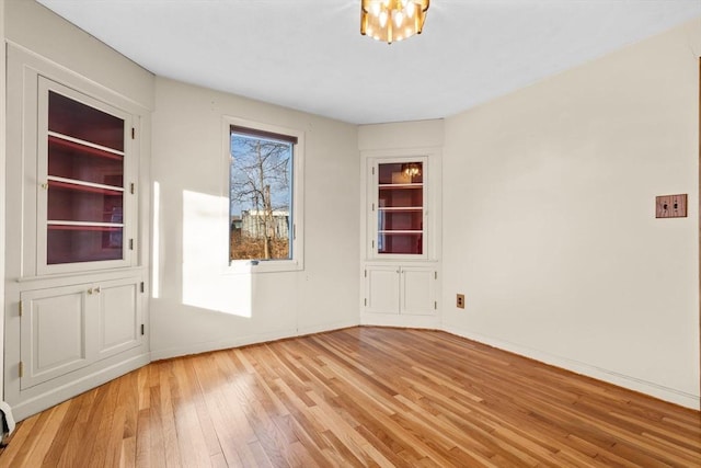 empty room featuring built in features and light hardwood / wood-style flooring