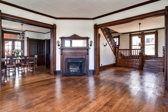 unfurnished living room featuring a fireplace, dark hardwood / wood-style floors, an inviting chandelier, and ornamental molding