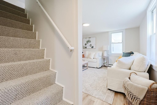 stairway featuring a baseboard heating unit and wood-type flooring