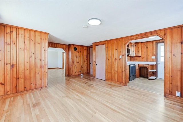 unfurnished living room featuring light hardwood / wood-style flooring and wood walls