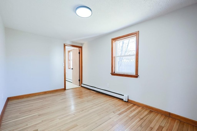 empty room featuring a baseboard heating unit and light hardwood / wood-style flooring