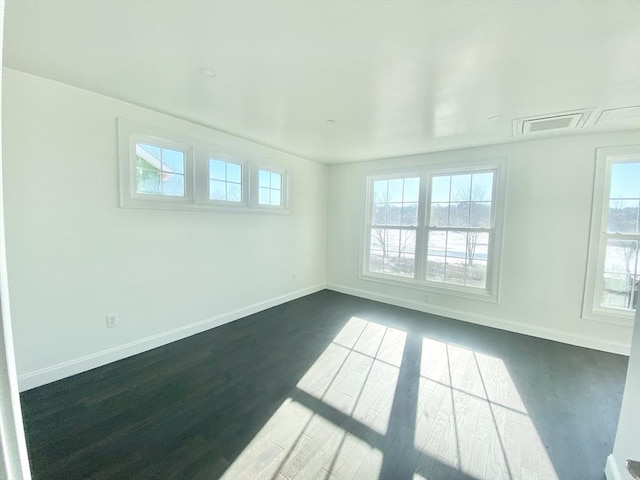 empty room with dark wood-type flooring and a wealth of natural light