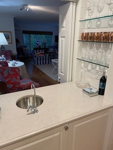 bar with light stone countertops, white cabinets, and wood-type flooring