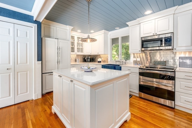 kitchen featuring appliances with stainless steel finishes, pendant lighting, and white cabinets