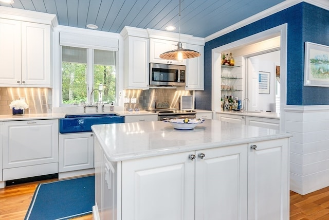 kitchen with sink, a kitchen island, decorative light fixtures, white cabinetry, and appliances with stainless steel finishes