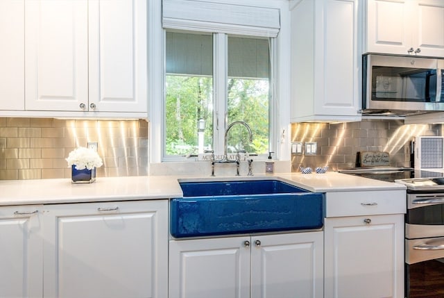 kitchen with decorative backsplash, sink, stainless steel appliances, and white cabinets