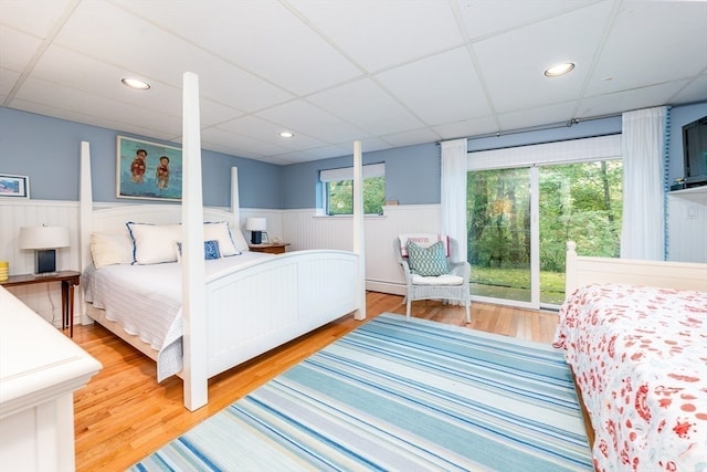 bedroom with wood-type flooring and a drop ceiling