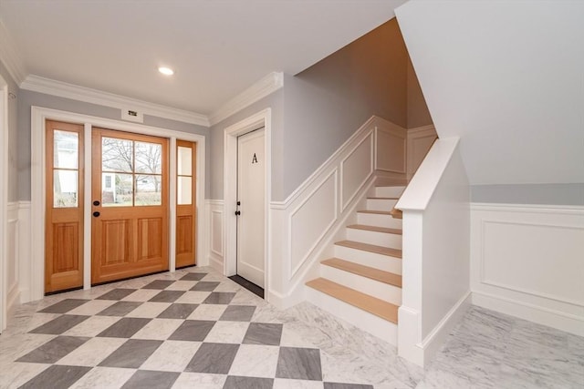 entrance foyer featuring a wainscoted wall, ornamental molding, and a decorative wall