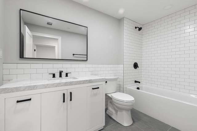 full bathroom with tile walls, tile patterned floors, vanity, toilet, and washtub / shower combination