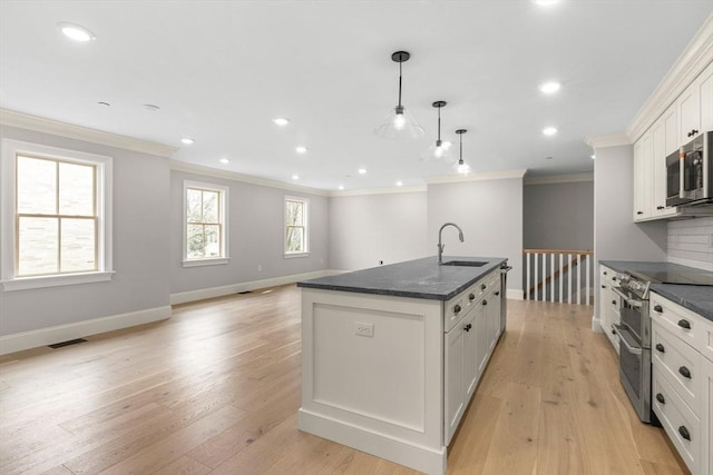 kitchen with stainless steel appliances, visible vents, ornamental molding, and a sink