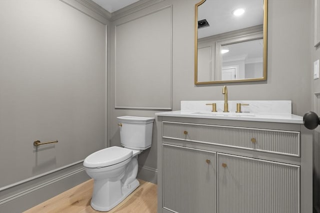half bath with toilet, baseboards, wood finished floors, and vanity