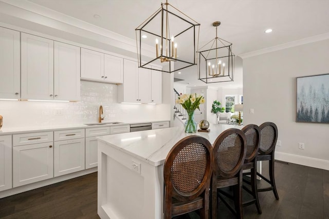 kitchen featuring a chandelier, a center island, dark wood finished floors, a sink, and ornamental molding