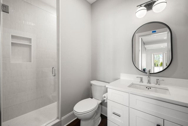 bathroom featuring a stall shower, toilet, vanity, and baseboards