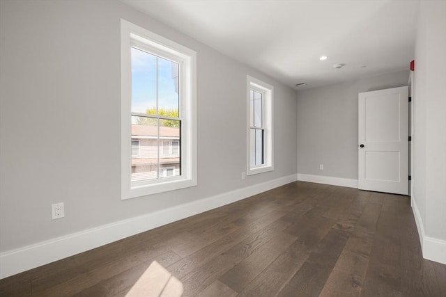 unfurnished room featuring dark wood-type flooring, baseboards, and recessed lighting