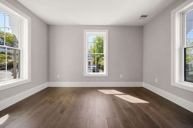 spare room featuring dark wood-type flooring and baseboards