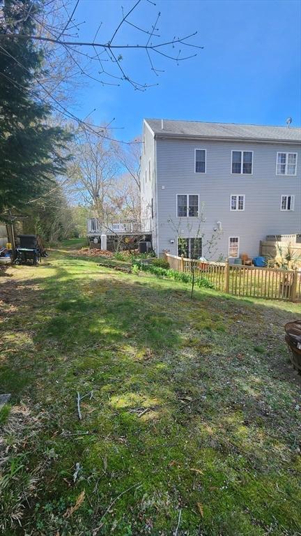 rear view of house featuring a lawn and fence