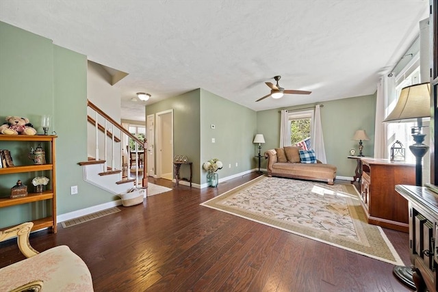 living area with ceiling fan, a textured ceiling, baseboards, wood finished floors, and visible vents