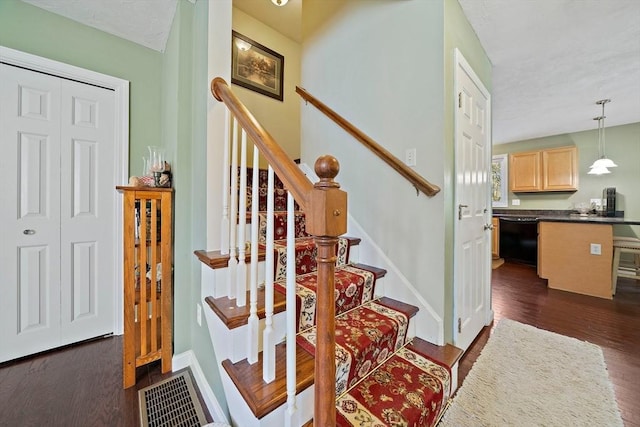 stairway featuring baseboards, wood finished floors, and visible vents