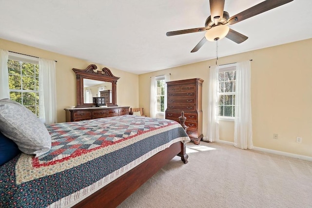 carpeted bedroom featuring a ceiling fan, baseboards, and multiple windows