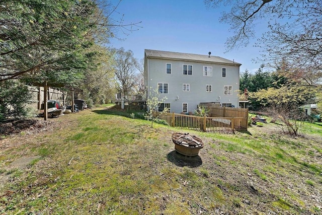 rear view of house featuring fence and a fire pit