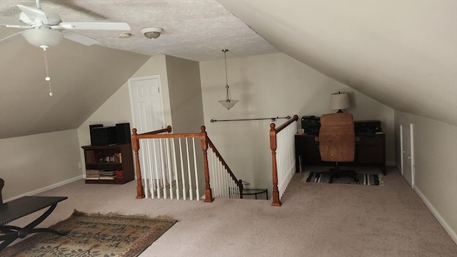 carpeted office space with baseboards, ceiling fan, and lofted ceiling