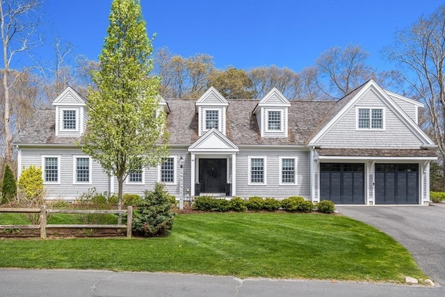 view of front facade with aphalt driveway, fence, and a front lawn