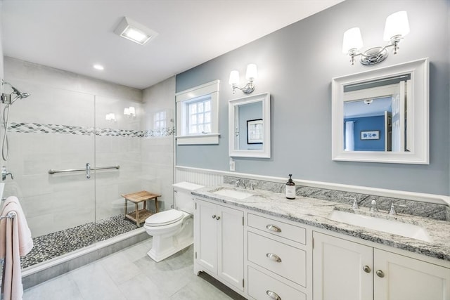 bathroom featuring a sink, double vanity, toilet, and a shower stall