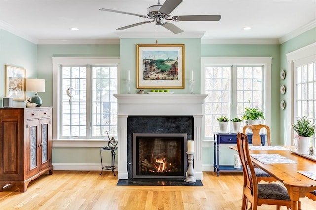 sitting room with wood finished floors, a lit fireplace, baseboards, and ceiling fan