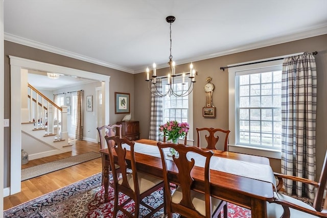 dining space with a wealth of natural light, a notable chandelier, and wood finished floors