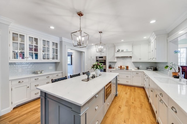 kitchen with a kitchen island, a sink, stainless steel appliances, white cabinets, and decorative backsplash