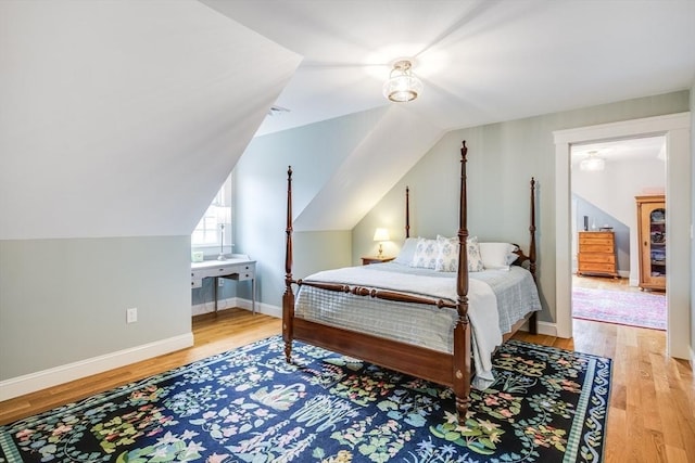 bedroom with vaulted ceiling, baseboards, and wood finished floors