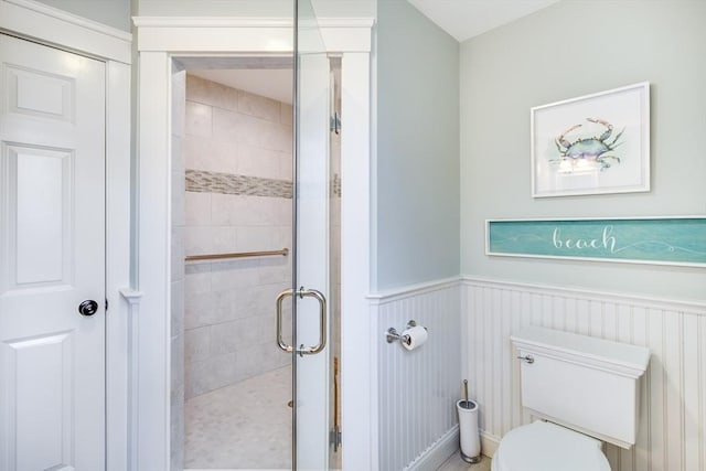 full bathroom with a wainscoted wall, toilet, and a shower stall