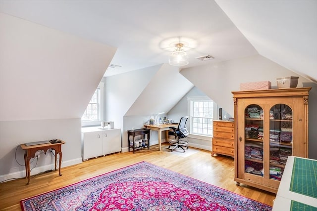 home office featuring lofted ceiling, baseboards, visible vents, and wood finished floors