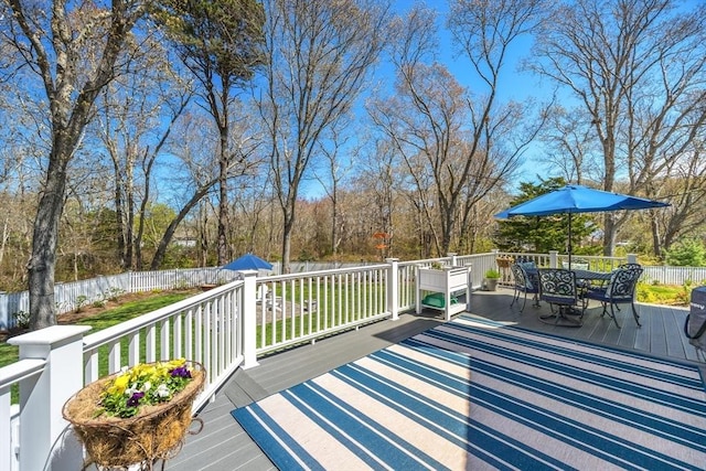 wooden deck featuring a yard, outdoor dining area, and a fenced backyard
